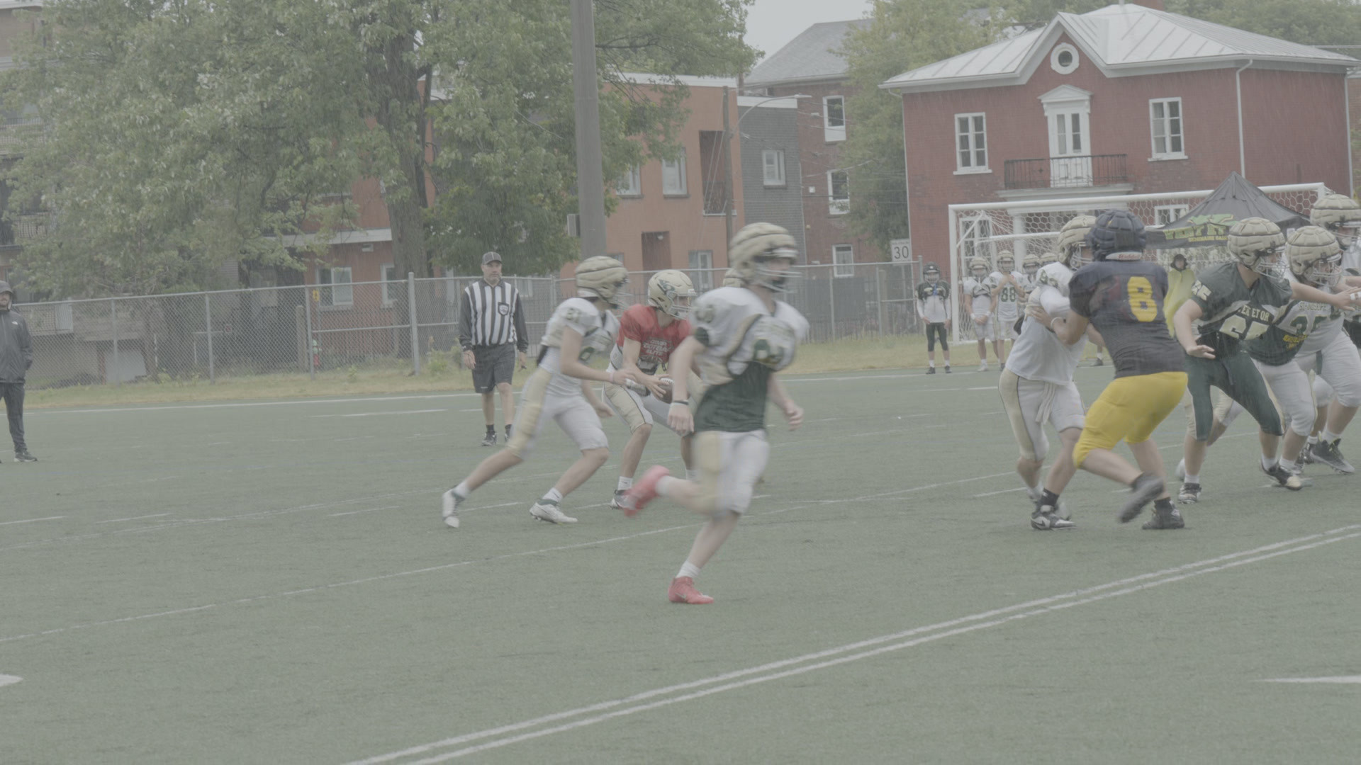 A football practice on a wet field, shot on a Sony FX30 in S-Log3: flat, gray and low in contrast, as recorded