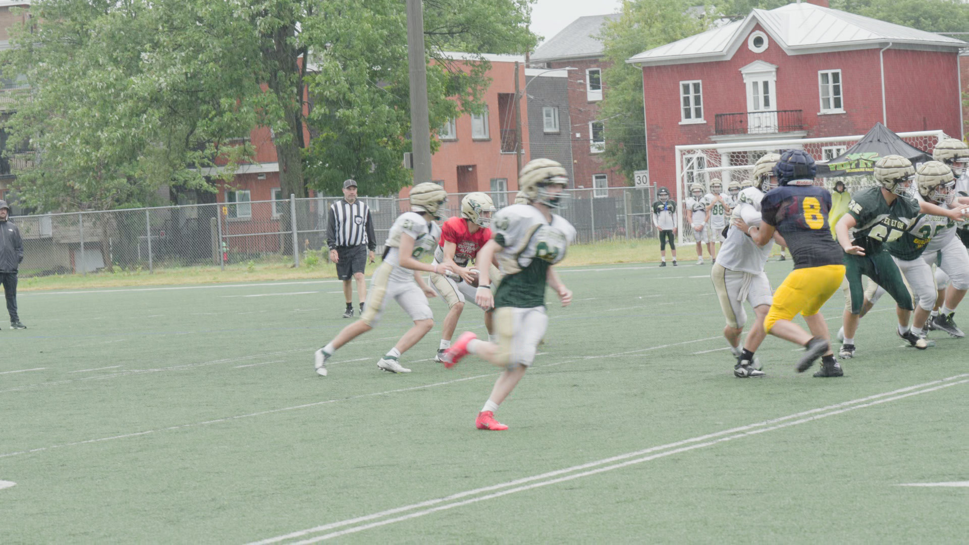 A football practice on a wet field through the free S-Log3 to Rec.709 LUT: green grass and a red brick house